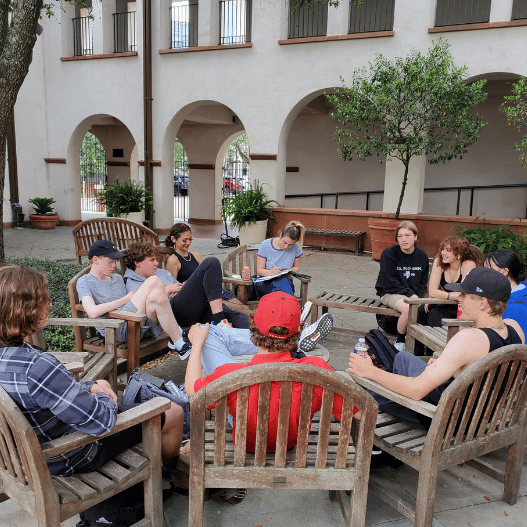 High school students in recovery talking and laughing in the Archway Academy courtyard, building community in a supportive sober school environment in Houston.